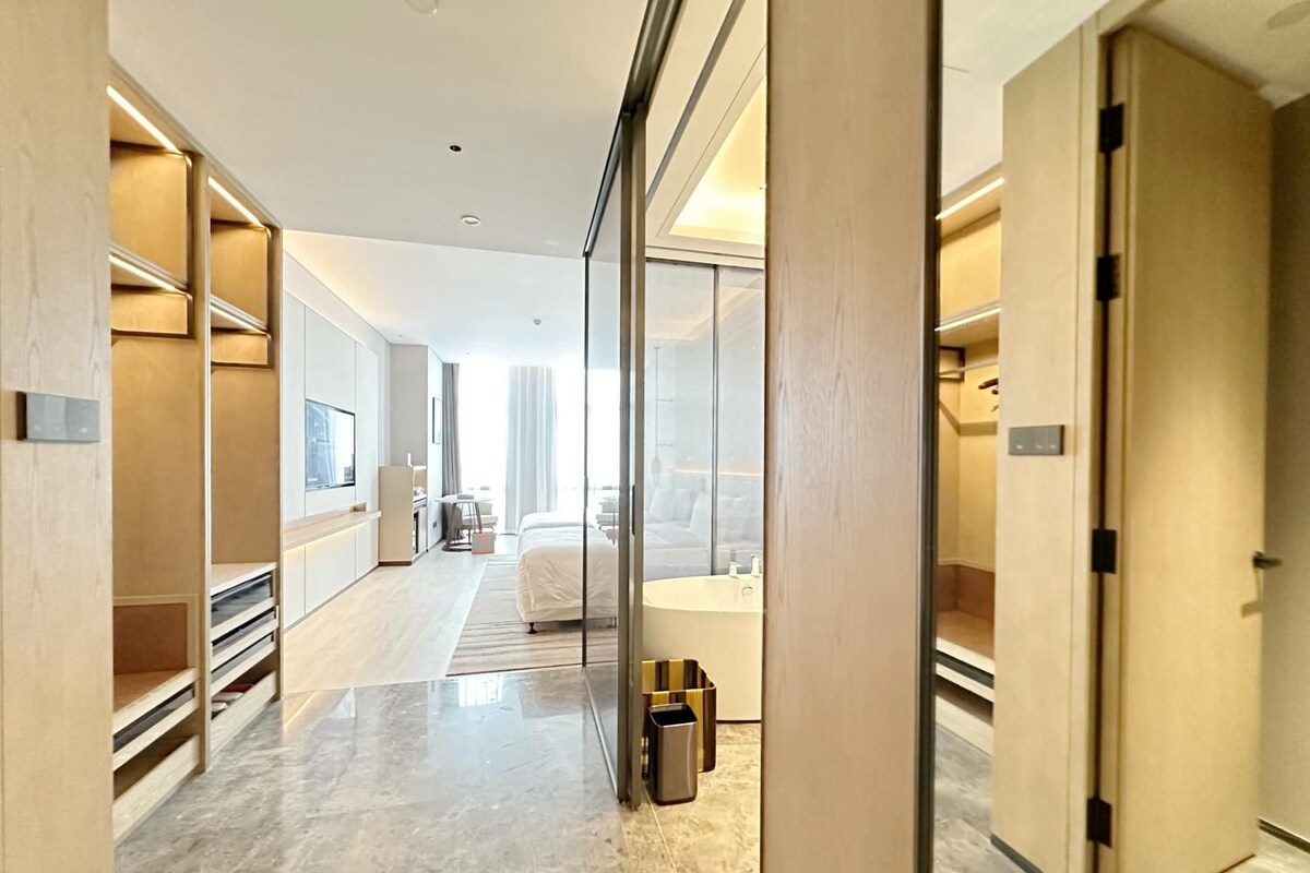A modern hotel room with a large bed, a bathroom, and a view of the city.