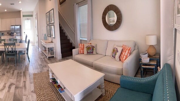 A spacious living area with a sofa, coffee table, and a television. There is a kitchen area with a dining table and chairs.