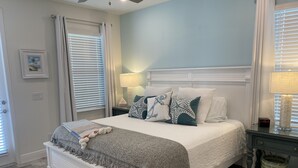A bedroom with a bed, bedside tables, a lamp, and a window with blinds.