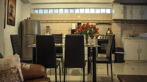 Eine moderne Küche mit Essbereich, ausgestattet mit Kühlschrank, Herd und Stühlen.