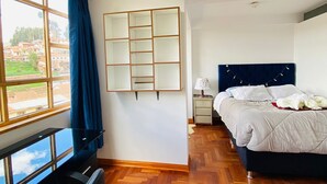 Ein Hotelzimmer mit großem Fenster, einem Bett, einem Schreibtisch und einem Stuhl.