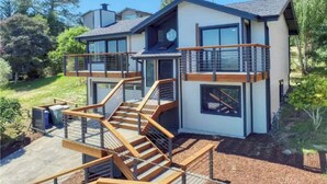 Une maison moderne à deux étages, dotée d’un balcon, d’un escalier et d’une terrasse.