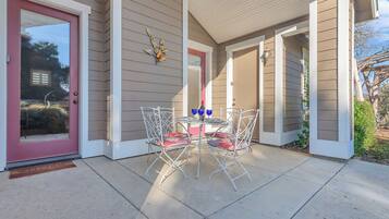 A covered patio with a table and chairs, a welcome mat, and a decorative wall piece.