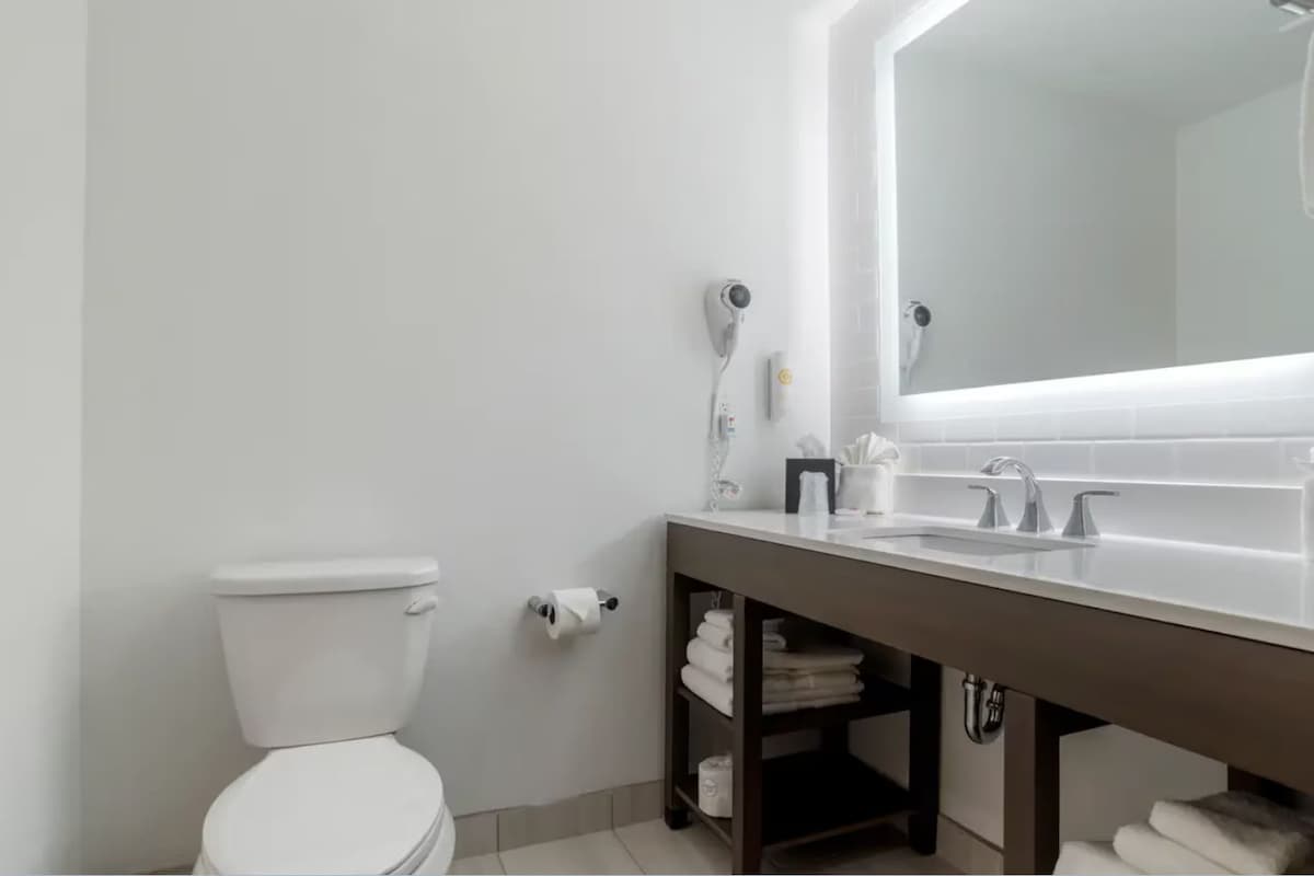 A modern bathroom with a toilet, a sink with a mirror, and a towel rack.