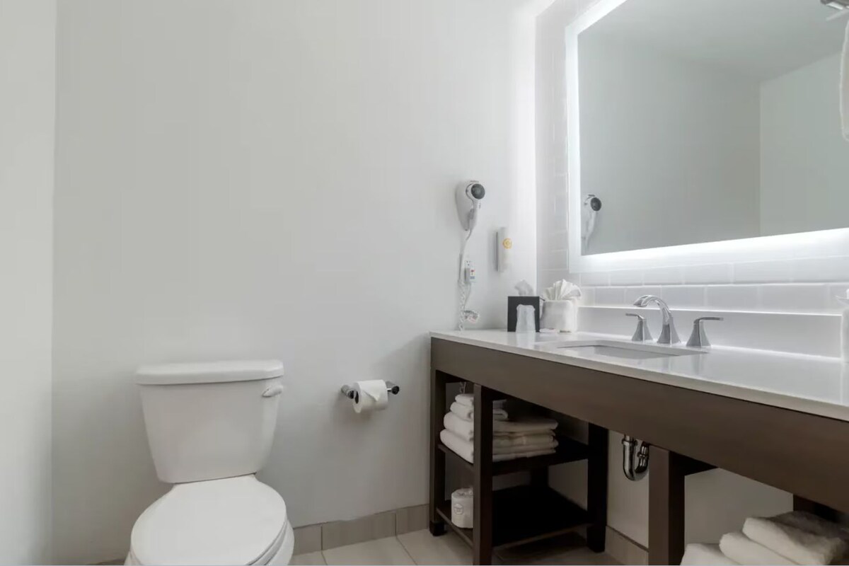 Een moderne badkamer met toilet, een wastafel met spiegel en een handdoekrek.