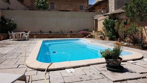A rectangular swimming pool with a tiled deck, surrounded by stone walls and potted plants. - Les Vignes de Théonie (VILLIE-MORGON)