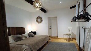 Een slaapkamer met een bed, nachtkastje, lamp en kapstok.