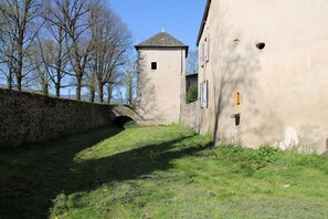 A stone bridge over a narrow waterway, a stone wall, and a building with a tower.