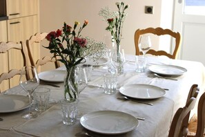 Una mesa de comedor dispuesta con platos, vasos y jarrones de flores.