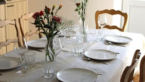 Et spisebord dækket med tallerkener, glas og vaser med blomster.