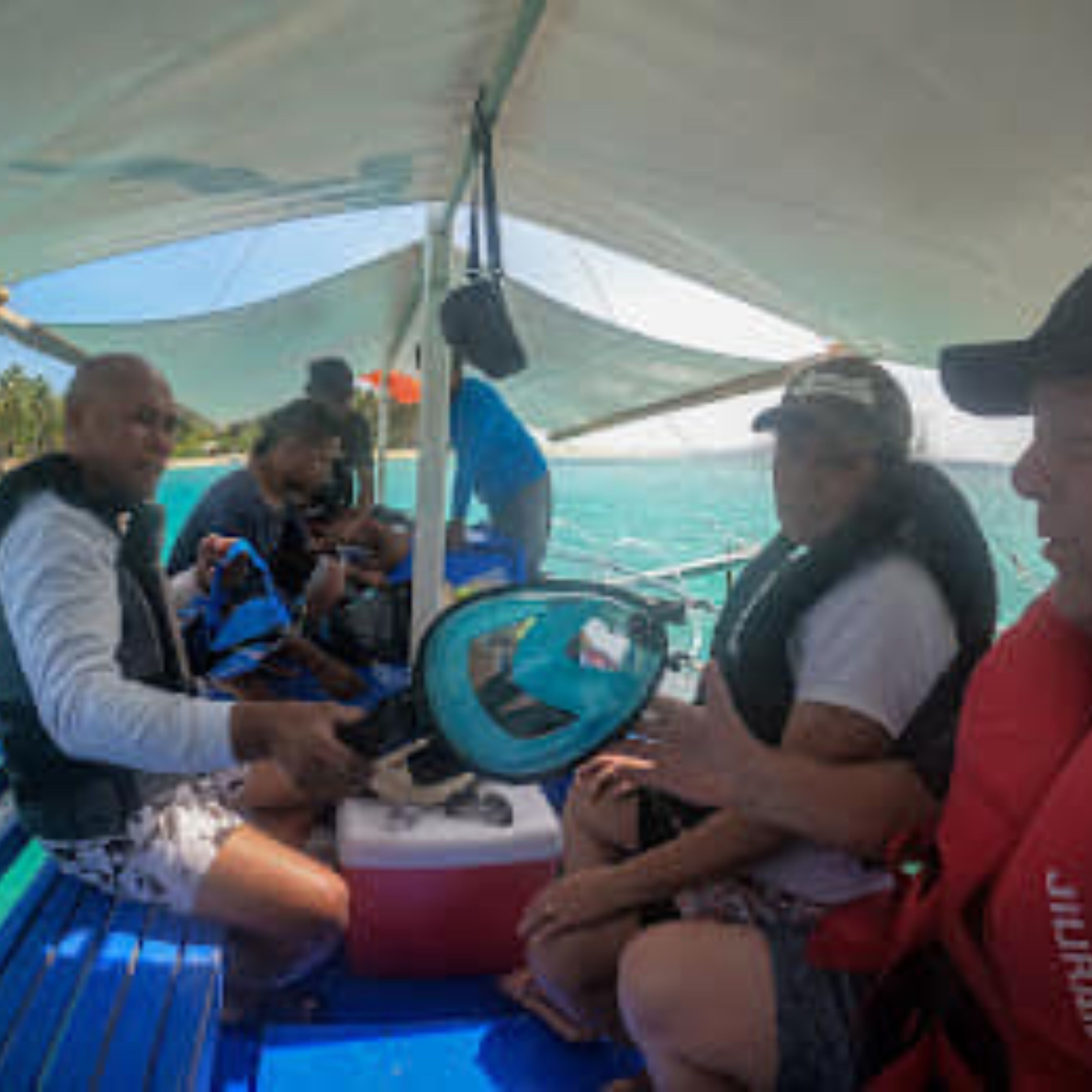 Un bote con cubierta azul, un timón y una persona con chaleco salvavidas.