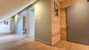A hallway with wooden flooring, a closed door, and a wall-mounted picture.
