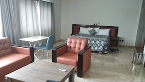 Una habitación de hotel con cama, sofá, sillón, mesita y mesita de noche.