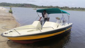 Un pequeño barco motor con toldo, amarrado en una orilla arenosa.