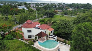 Una casa con piscina, rodeada de vegetación exuberante y vistas a una masa de agua distante.