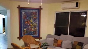 Una sala de estar con un sofá gris, una silla de mimbre y una pequeña mesa redonda con una planta.