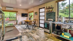 A kitchen with a stove, sink, and dining area with chairs. - Pura Vidaville. Jungle Oasis w/AC, Fast WiFi & Private River Access-Tenorio Park (Bijagua)