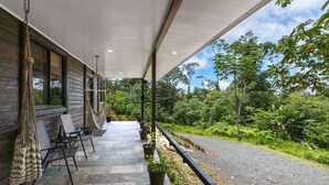 A covered outdoor area with stone flooring, seating, and potted plants. - Pura Vidaville. Jungle Oasis w/AC, Fast WiFi & Private River Access-Tenorio Park (Bijagua)