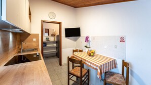 Une cuisine compacte dotée d’un plan de travail en bois, d’un évier et d’un coin repas avec une nappe à rayures et des chaises.