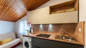 Une petite cuisine équipée comprenant un lave-linge intégré, un évier et un plan de travail en bois.