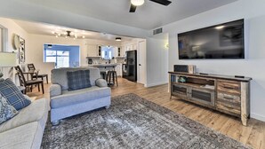 Een moderne woonkamer met een grijze bank, een flatscreen televisie en een houten tv-meubel.