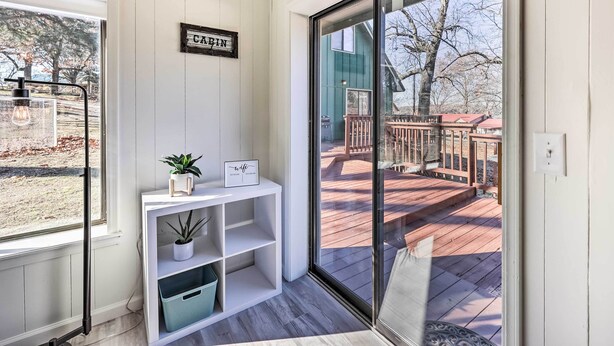 Een kamer met een schuifglazen deur naar een terras, een witte console tafel met een plant en een bord, en een bord met daarop 'CABIN' aan de muur.