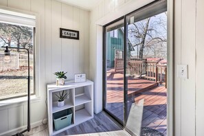 Et værelse med en skydedør til en terrasse, et hvidt konsolbord med en plante og et skilt, samt et skilt med teksten 'CABIN' på væggen.