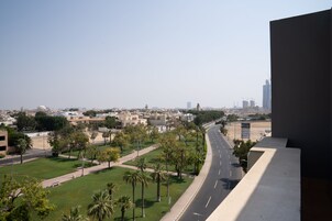 A cityscape with a wide road, palm trees, and buildings in the background.