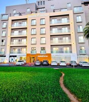 Un hôtel à plusieurs étages, doté d’une entrée principale, de balcons à chaque étage et d’un espace de stationnement à l’avant.