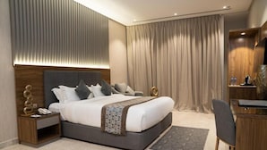 A modern hotel room with a large bed, bedside tables, a desk, and a chair.