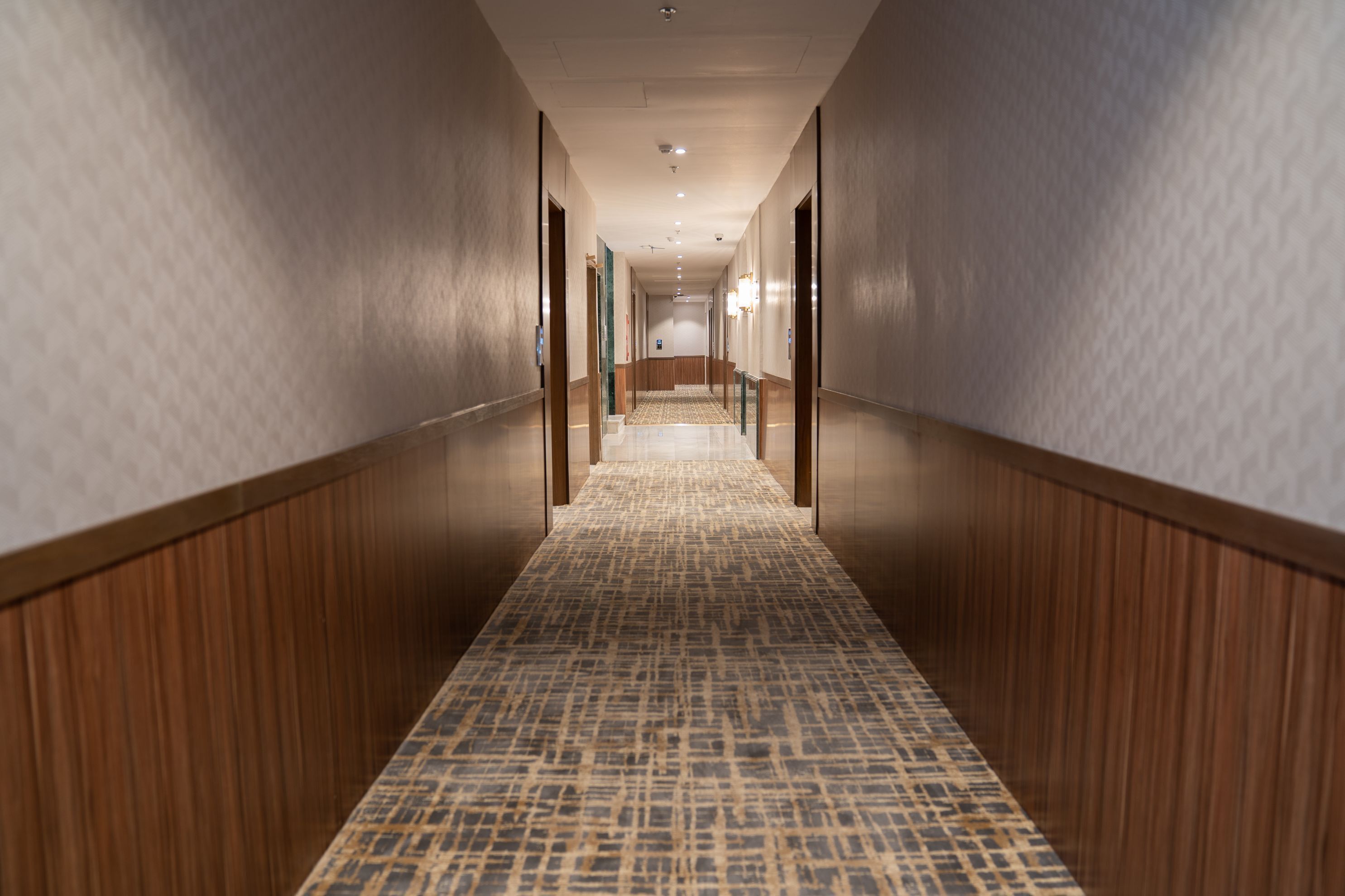 Un pasillo largo y estrecho con paneles de madera en las paredes y una alfombra estampada.