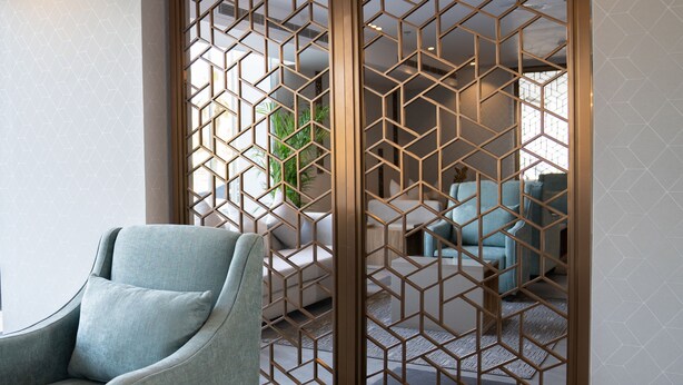 A modern living room with a geometric patterned partition, a light blue armchair, and a sofa with light blue cushions.