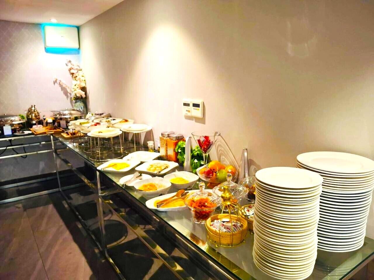 A buffet setup with various dishes and stacked plates.