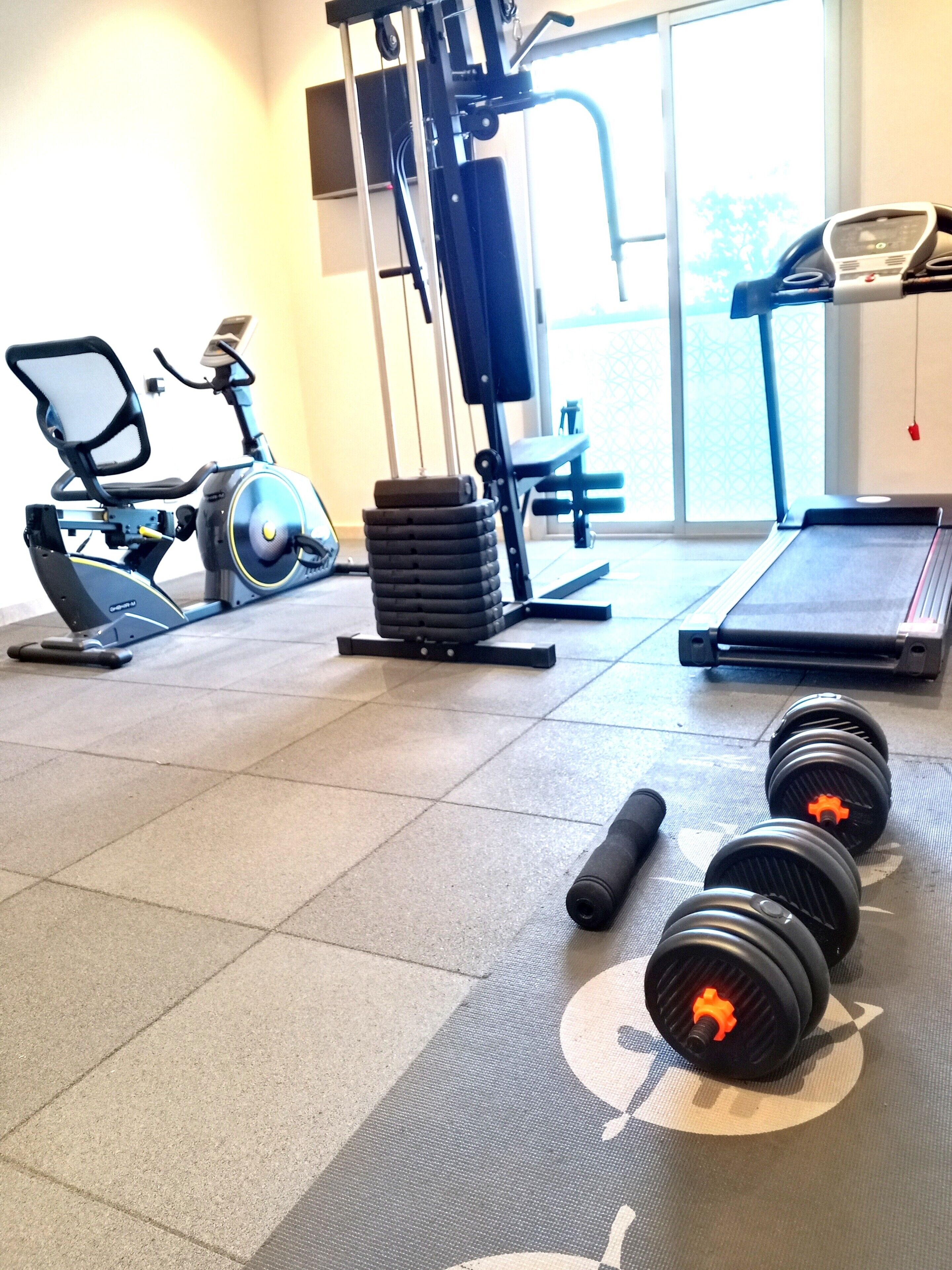 Ein Fitnessstudio mit Trainingsgeräten, Laufband und Kurzhanteln.