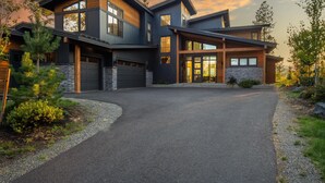 Een modern huis met twee verdiepingen, een stenen gevel, grote ramen en een oprit naar de garage.