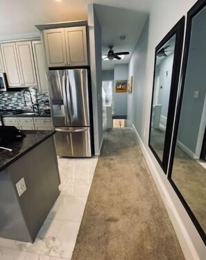 Contemporary kitchen with stainless steel appliances, light cabinetry, and dark countertops.