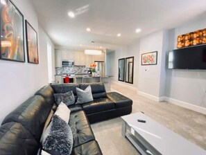 Relax in this stylish living space with a comfortable sofa, flat-screen TV, and fully equipped kitchen.