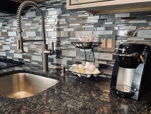 Enjoy cooking in this well-equipped kitchen with a granite countertop, stainless steel sink, and high-arched faucet.