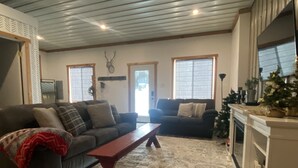 A living room with two sofas, a coffee table, a patterned rug, a fireplace, and a deer head decoration on the wall. - Comfortable and cozy getaway in the heart of Crosslake (Crosslake)