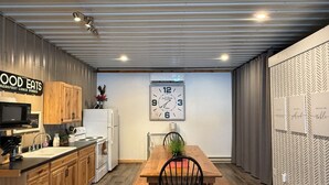 A modern kitchen with wooden cabinets, a microwave, a refrigerator, and a dining area with a wooden table and chairs. - Comfortable and cozy getaway in the heart of Crosslake (Crosslake)