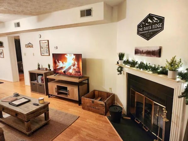 A living room with a fireplace, a television, wooden furniture, and a sign that reads "The Davis Ridge". - Free Firewood, Mt Views, Skiing, Heated Pool (Davis)