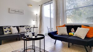Una sala de estar moderna con dos sofás, una mesita y un ventanal con cortinas.