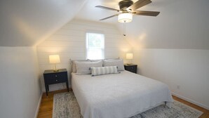 A bedroom with a bed, two bedside tables with lamps, a ceiling fan, and a window. - NickelPlate Beach House w Street Legal Golf Cart (Huron)
