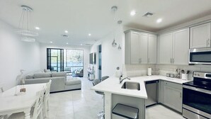 A modern kitchen with white cabinets, stainless steel appliances, and a central island. - Cozy new construction townhome.  (Naples)
