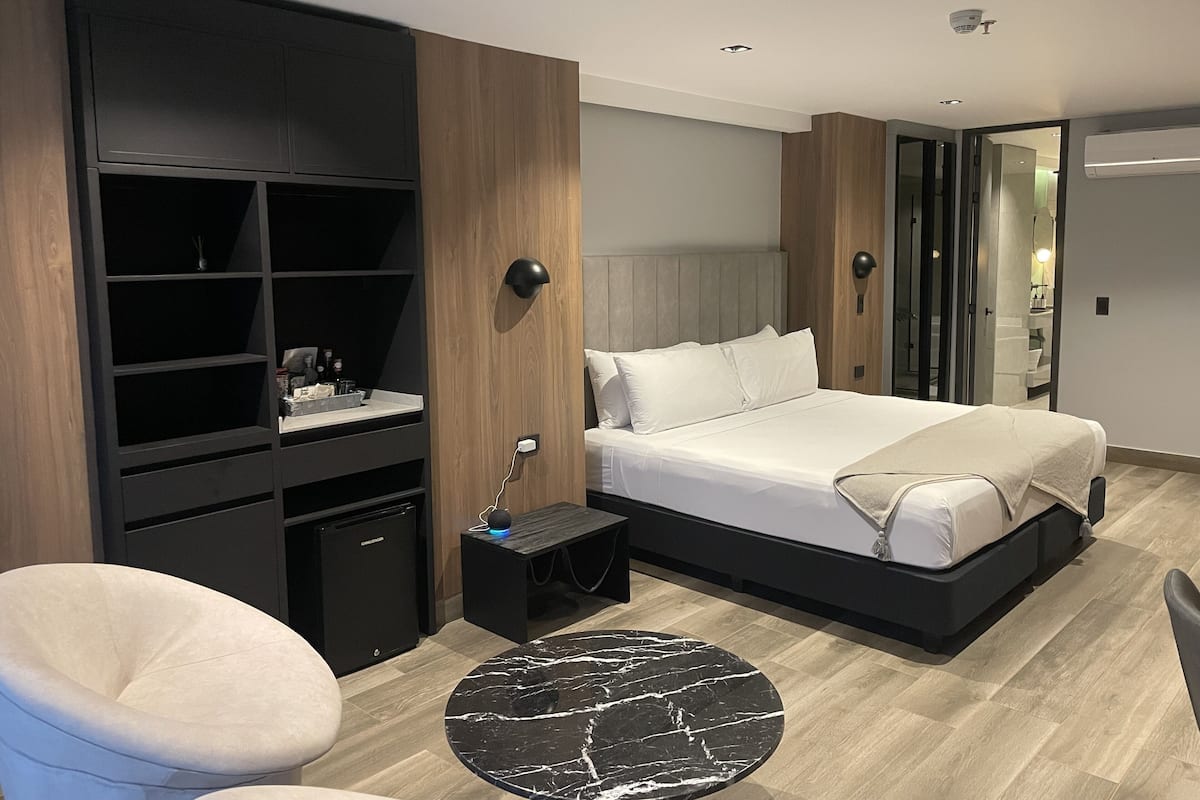 A modern bedroom with a bed, a desk, a chair, and a round table.