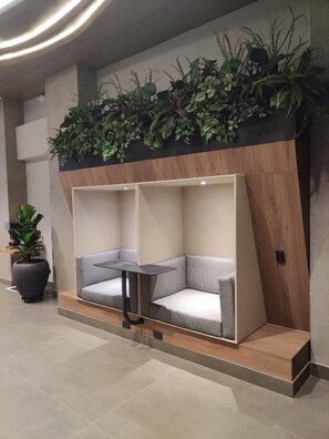 Un área de estar moderna con una mesa integrada, rodeada de bancos acolchados, y un jardín vertical en la parte superior.