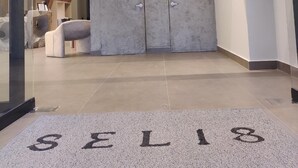 A modern reception area with a glass door, a reception desk, and a seating area. - HOTEL SELIS (Medellín)
