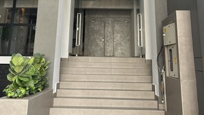The entrance to the SELIS Wellness Hotel with a modern design, featuring a glass facade, a staircase leading to the entrance, and a sign above the doors. - HOTEL SELIS (Medellín)