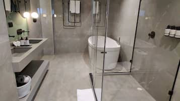 Un baño moderno con ducha envuelta en vidrio, una bañera independiente y un tocador con lavamanos y espejo.