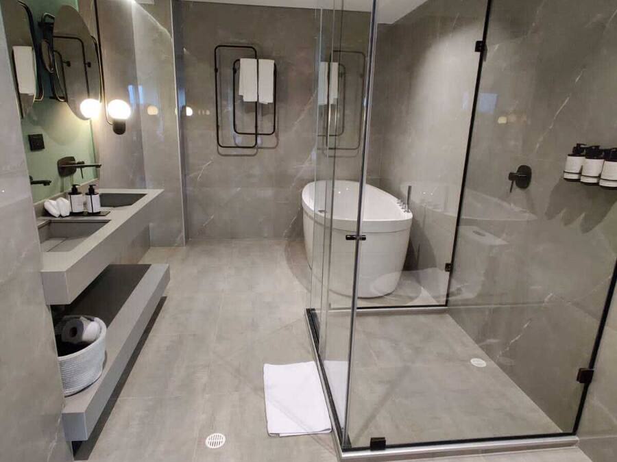 A modern bathroom with a glass-enclosed shower, a freestanding bathtub, and a vanity with a sink and mirror.